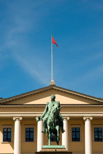The Royal Norwegian Castle in Oslo against blue sky. The statue is of King Karl Johan