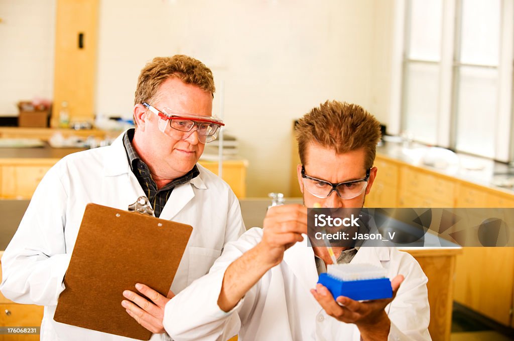 Teacher watching student A teacher watching a student in a laboratory.  Focus on the Teacher's eyes with limited depth of field Adult Stock Photo