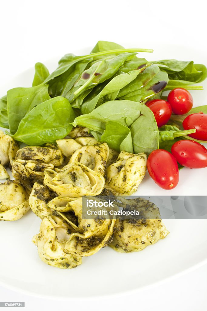 Tortellini Pasta Salad "Plate of delicious homemade tortellini pasta with pesto sauce, pine nuts, spinach and baby plum tomatos." Cheese Stock Photo