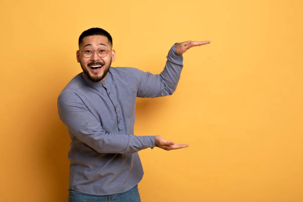 istock Cheerful Young Asian Man Measuring Invisible Object With His Hands 1760697576