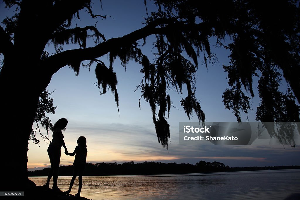 Madre e figlia di tempo di qualità sotto albero al tramonto Silhouette - Foto stock royalty-free di Muschio - Flora