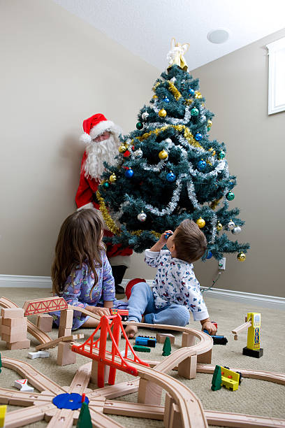 istock Children Looking Over Their Shoulders Seeing Santa Behind Tree 176072290