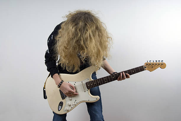 A studio shot of a girl holding an electric guitar and waving her hair.