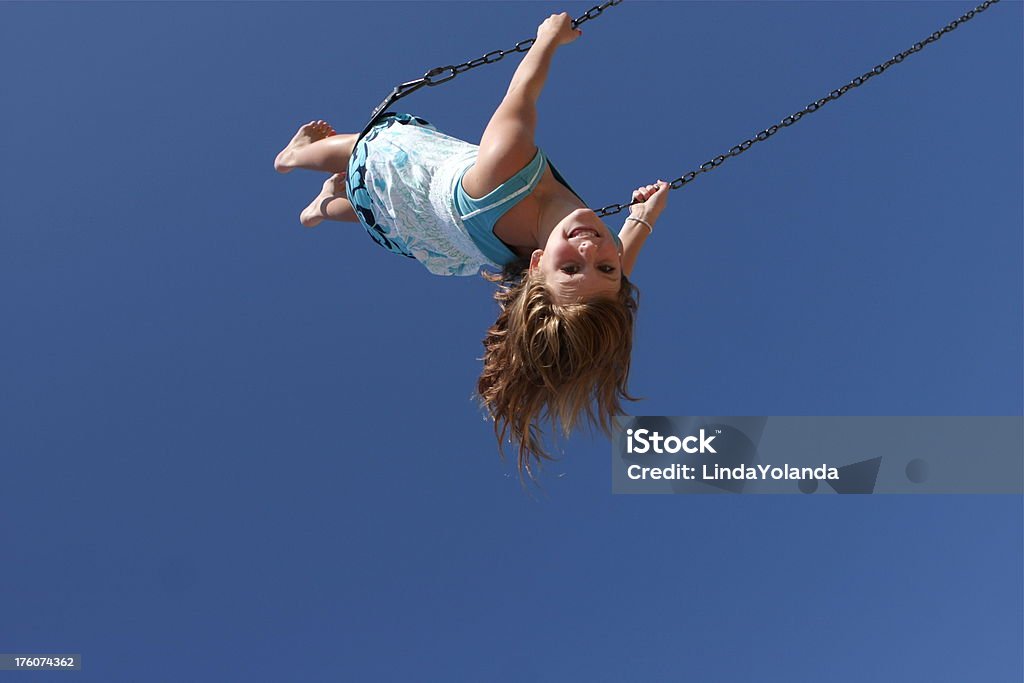 Child on Swing A little girl is swinging high against a blue sky. Low angle view. Plenty of copy space. Child Stock Photo