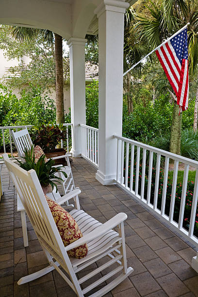 Rocking Chairs on a Classic Front Porch Americana A porch with rocking chairs at a rural Florida home.  An American flag flies at the front of the house. front porch stock pictures, royalty-free photos & images