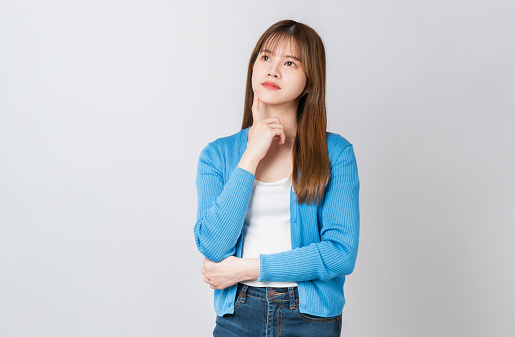 Young Asian woman standing pointing finger and think something with crossed arms against on white background.