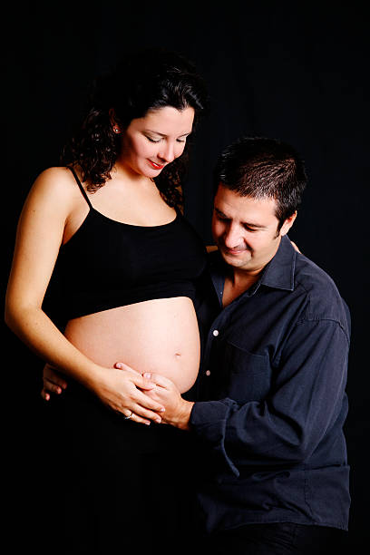 Parents To Be "Young mom and dad look on to the belly in anticipation.For more of my similar images, please follow the banner link below:" 3 months pregnant belly stock pictures, royalty-free photos & images