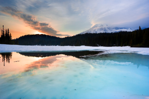 A mountain lake with thawing snow at the end of winter. Mt Rainier and the Reflection Lake at sunset.