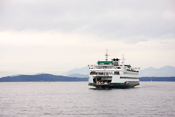 Washington State Car Ferry on Puget Sound Washington State car and passenger ferry crossing Puget Sound. Olympic mountains in the background. bainbridge island photos stock pictures, royalty-free photos & images
