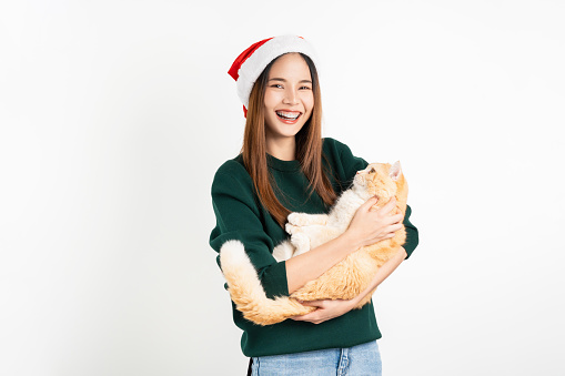 Smile Asian woman in Christmas attire and holding cute cat on white background.