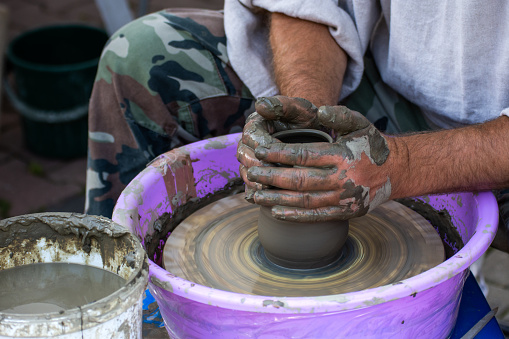 Hands of a potter, creating an earthen jar on the circle.