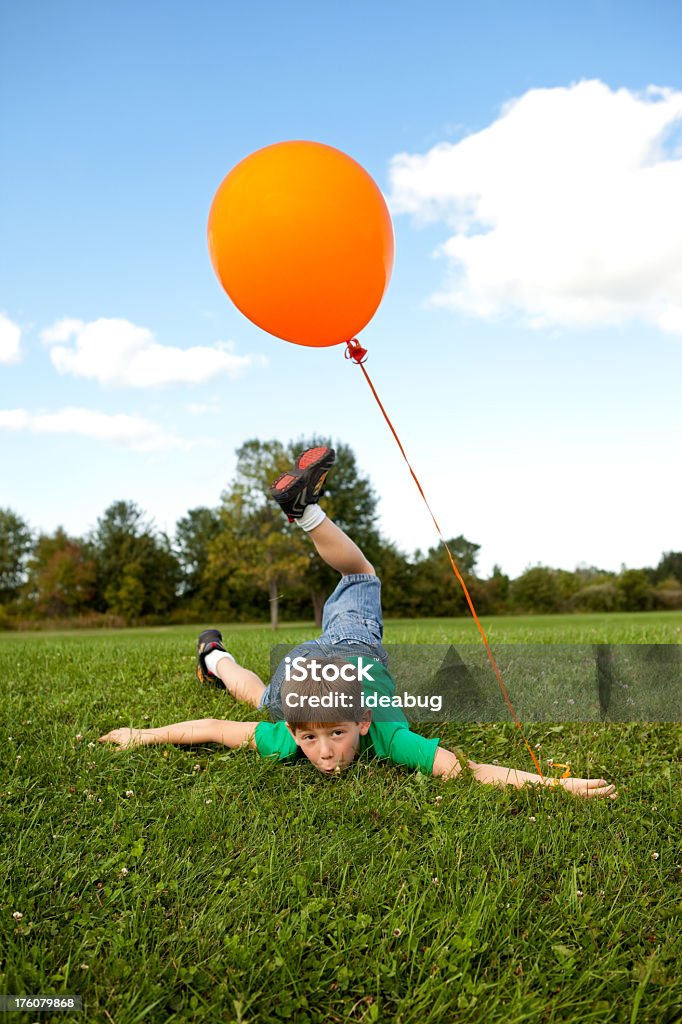 Garçon avec Ballon de baudruche voyages et Falls pendant la course à l'extérieur - Photo de Enfant libre de droits