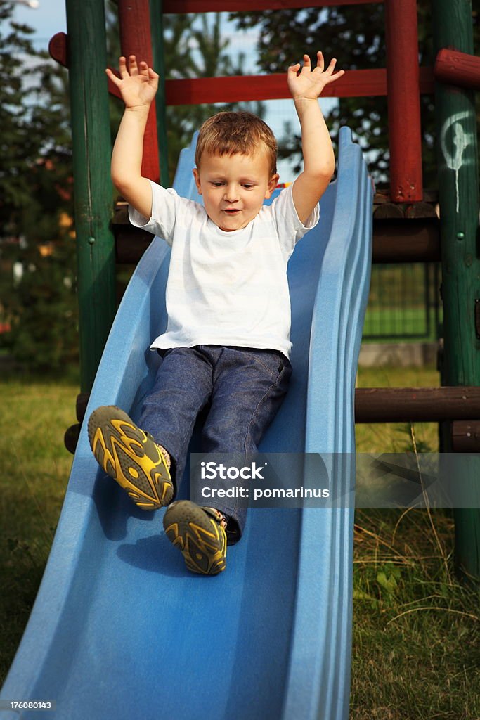 Slide Preschooler is sliding at playground. Boys Stock Photo