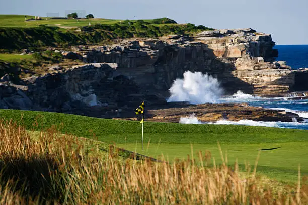 A beautiful golf course against a dramatic ocean background with Copy Space. Focus on hole and putting green.