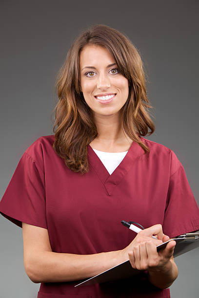 Female nurse with pen and tablet Please view more medical professional photos here: red medical scrubs stock pictures, royalty-free photos & images
