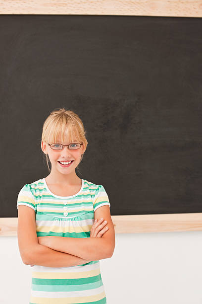 Happy pretty girl standing in front of a blackboard