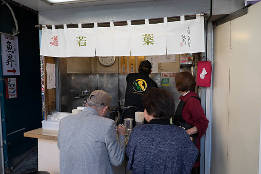 TOKYO, JAPAN - MARCH 27, 2015 : Tourist eating noodle at the Noodle restaurant at Tsukiji Fish Market in Tokyo.