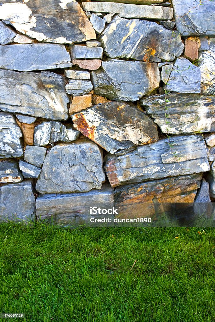 Rough Dry Stone Wall and Green Grass Agricultural Field Stock Photo