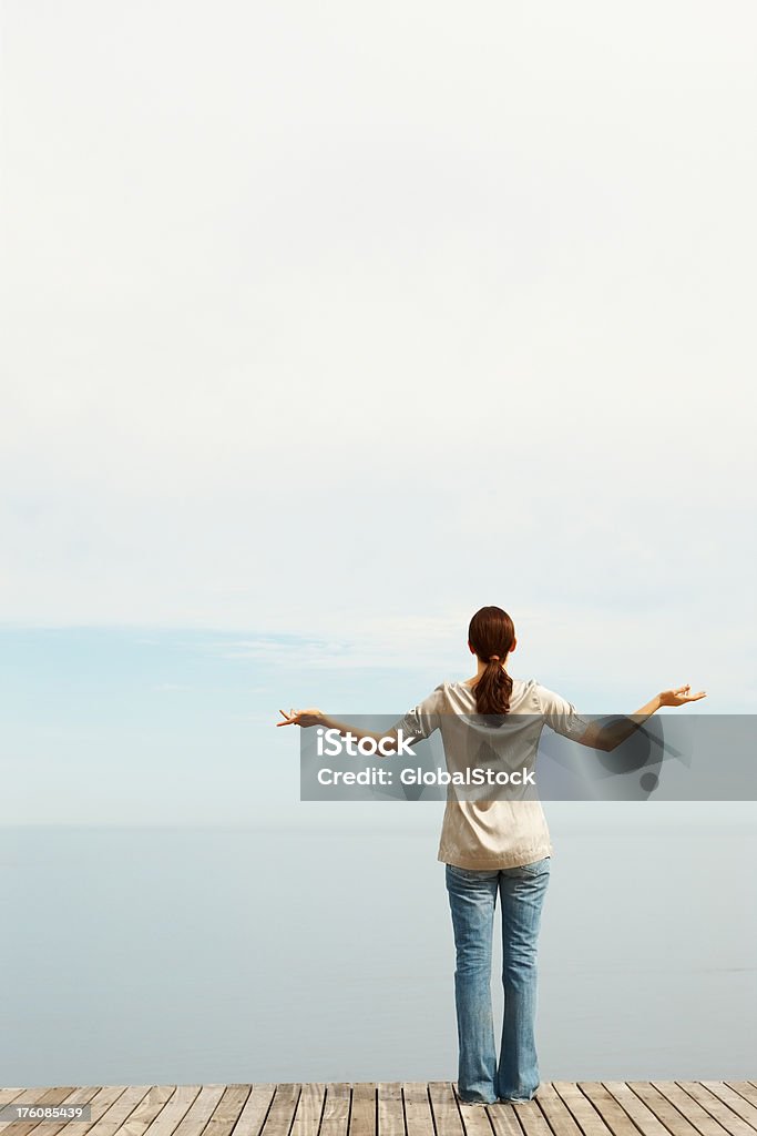 Donna guardando verso il mare, in piedi sul molo - Foto stock royalty-free di Abbigliamento casual