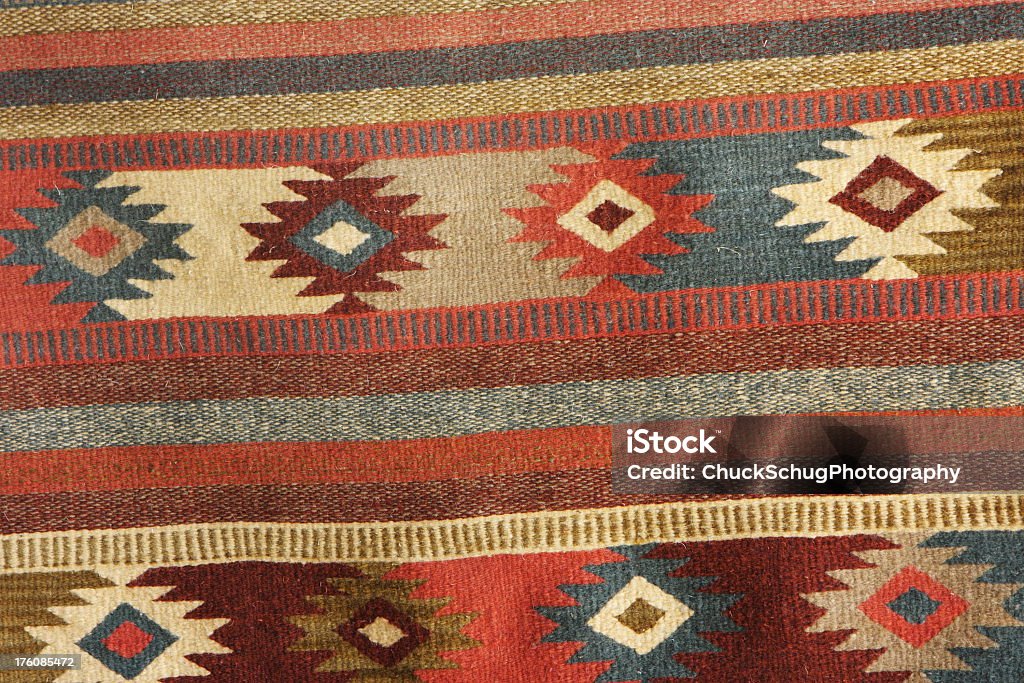 Navajo Blanket Rug Fabric Design Navajo blanket woven wool design in deep pastel colors.  The Navajo stained their yarns for fabrics using natural items from the surroundings - beige from corn silk, tan from brown onion skin, maroon from Juniper bark, amber from Juniper Mistletoe, olive-yellow from sagebrush, gray from Indian Paintbrush, brown from the Gambel Oak, dark green from red onion skin, lavender from Holly berries, dusty orange from canaigre root - just a few of the earthtone colors produced for coloring yarns and other items.  Arizona, 2010. Indigenous North American Culture Stock Photo