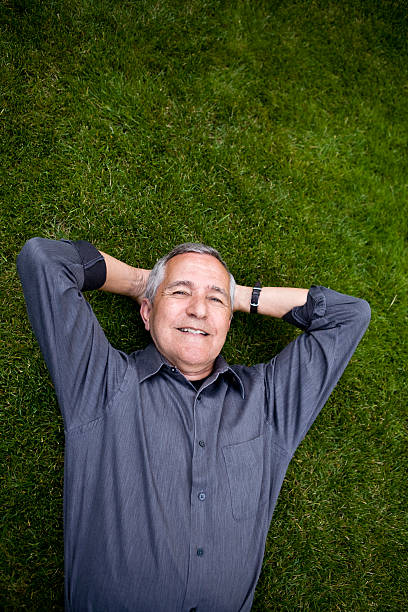 istock Senior man lying on the grass with hands behind head 176085831