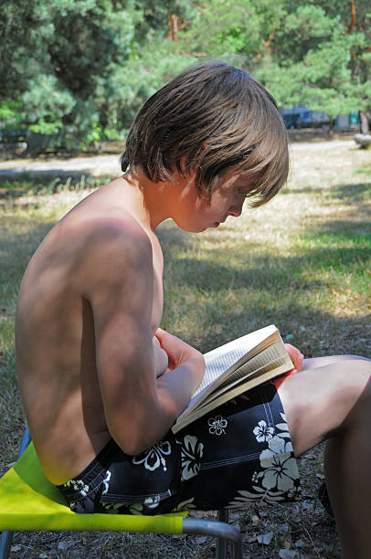 istock Boy reading a book sitting in nature 176085989