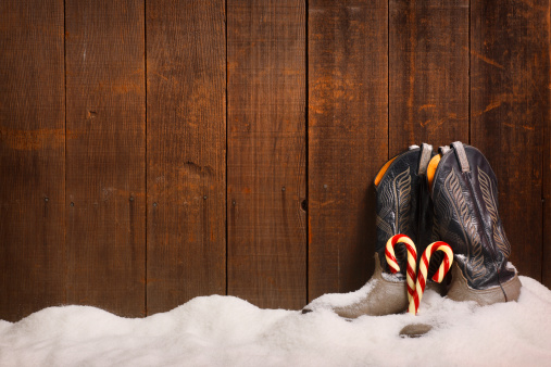 Two candy canes resting against two cowboy boots in the snow.To see more holiday images click on the link below: