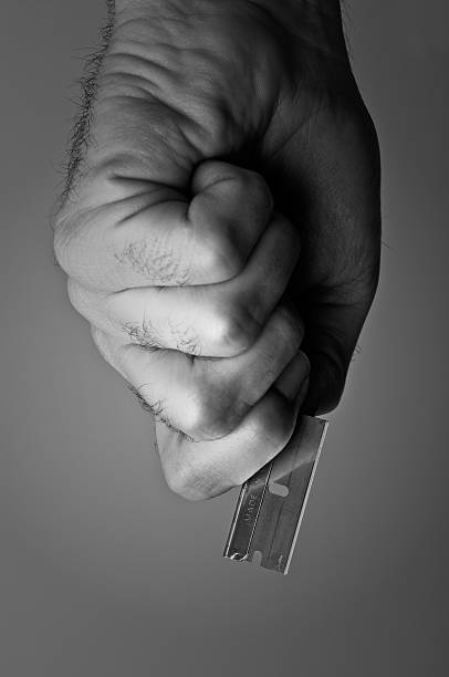 dangerous hand with razor blade in black and white