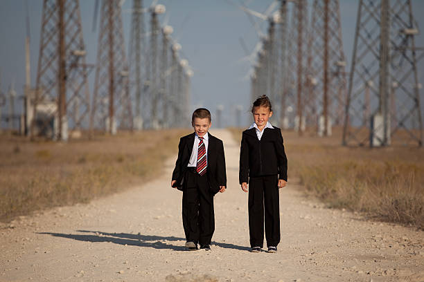 children on the road among the windmills. six-year boy and girl in business suits