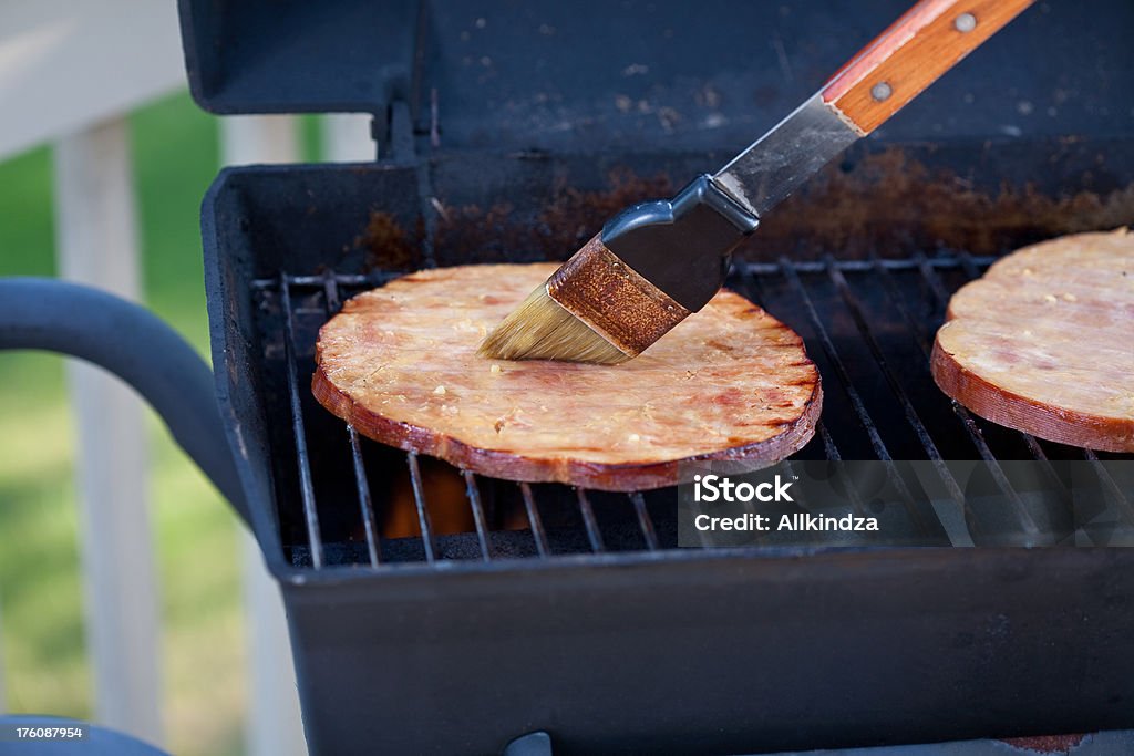 basting grilled ham steaks 2 ham steaks on an old grilled being brushed with marinade using an rusty bbq brush Applying Stock Photo