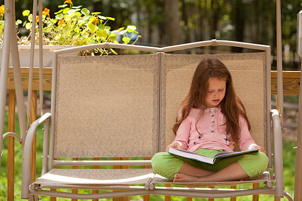 istock girl sit on seesaw and reading the book 176089108