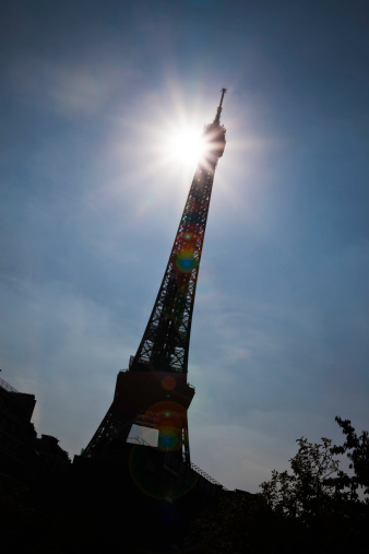 Eiffel tower silhouetted by sun with lens flare