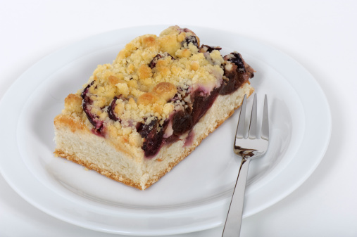 A slice of fresh plum cake on a white plate.Click here for related images: