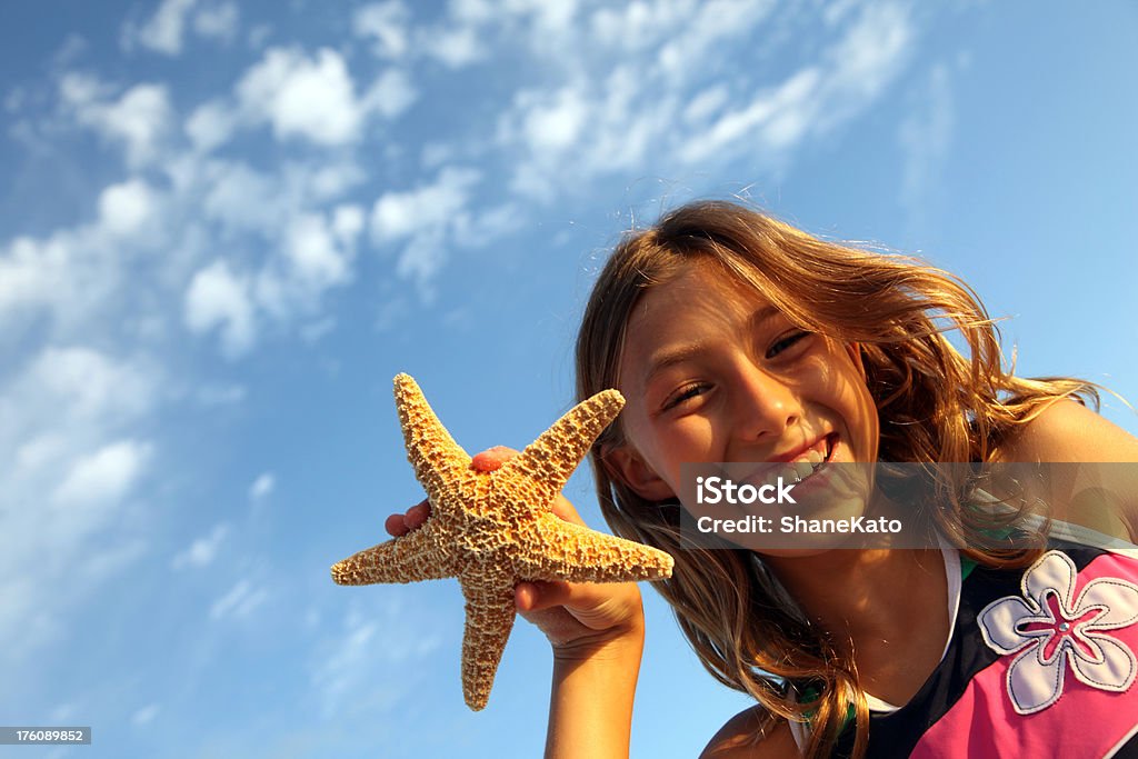 Fille souriante au vacances tenant une étoile de mer - Photo de Destin - Floride libre de droits