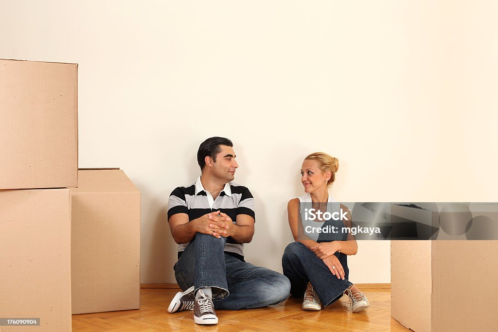 Moving House Young couple sitting on parquet floor and resting at the moving day. 25-29 Years Stock Photo