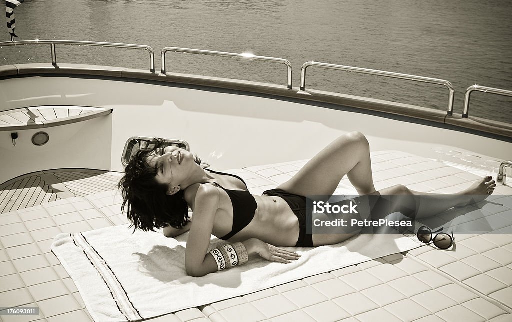 Beautiful woman sunbathing and relaxing on a luxury yacht Beautiful woman sunbathing and relaxing on a luxury yacht. Desaturated and toned image.More of this beauty in this lightboxes Fashion Stock Photo