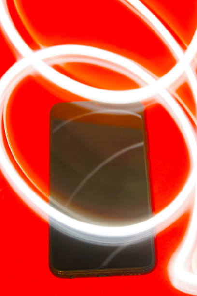 istock mobile phone on red background with white light strokes 1760931197