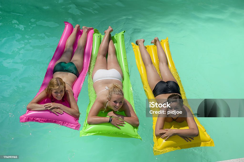 Tre ragazze in piscina colorato gommoni - Foto stock royalty-free di Accanto