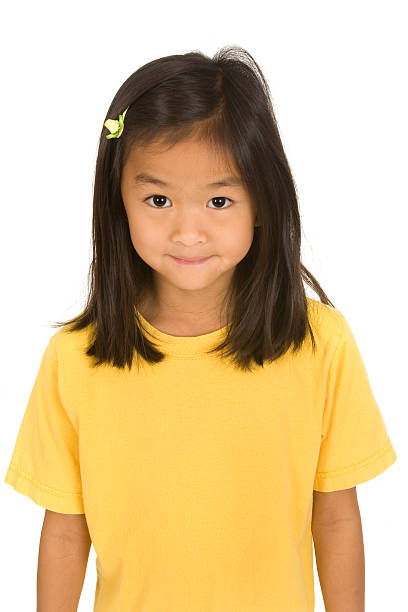 Portrait of a young girl with pigtails, gazing upwards with a thoughtful expression against a blurred green background.