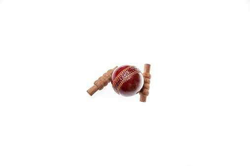 Red cricket ball and bails are on isolated white background