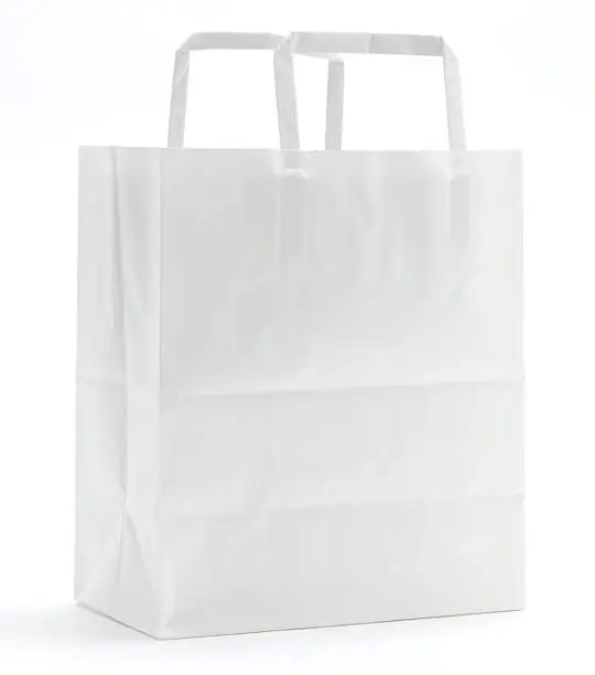 Blank white paper shopping bag with paper handles and some fold creases on a white background.