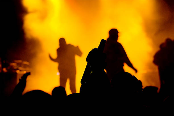 drinking crowd on rap concert concert crowd rising a bottle. silhouetes of rappers on stage rap stock pictures, royalty-free photos & images