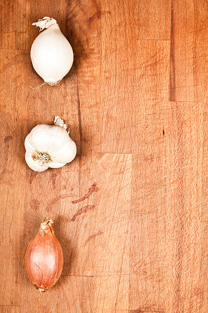 istock Onion, Garlic and Scallion bulbs on wooden chopping board 176097113