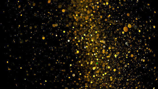 Close-up of yellow coloured glitter against black background.
