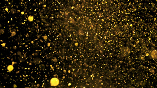 Close-up of gold coloured glitter against black background.