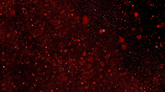 Close-up of red coloured glitter against black background.