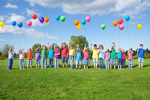 お子様のグループに立つラインに風船 - child waiting in line in a row party ストックフォトと画像