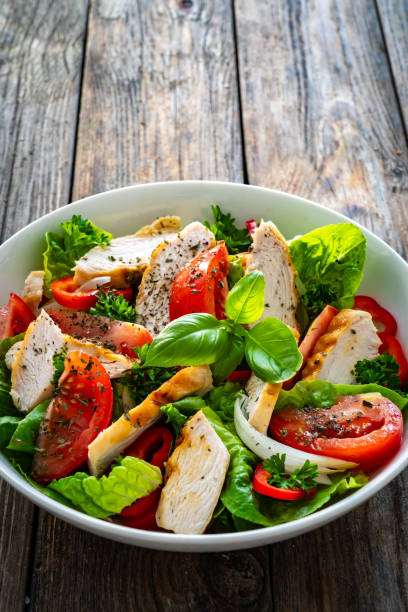 istock Caesar style salad  - fresh vegetables with grilled sliced chicken breast on wooden table 1761003148