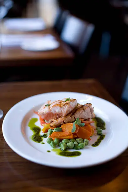 "Grilled salmon fillets with fresh peas, steamed carrots and pesto sauce."