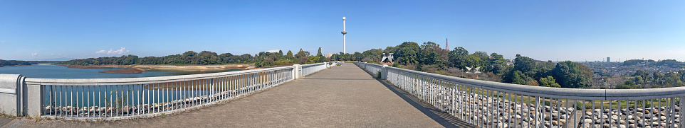 A clear autumn picture of Lake Tama was taken separately with a wide-angle lens and combined using software to create a single panoramic photo. Photography information: October 27, 2023, at the dam site of Lake Tama, Higashimurayama City, Tokyo, Japan.